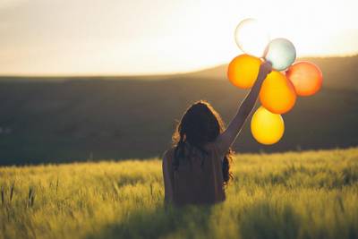 woman happy holding balloons in grassfield